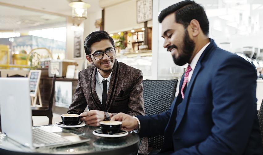 Two business professionals discussing investment opportunities over coffee, representing EB5 investors and employment-based visa applicants planning their U.S. immigration strategy.
