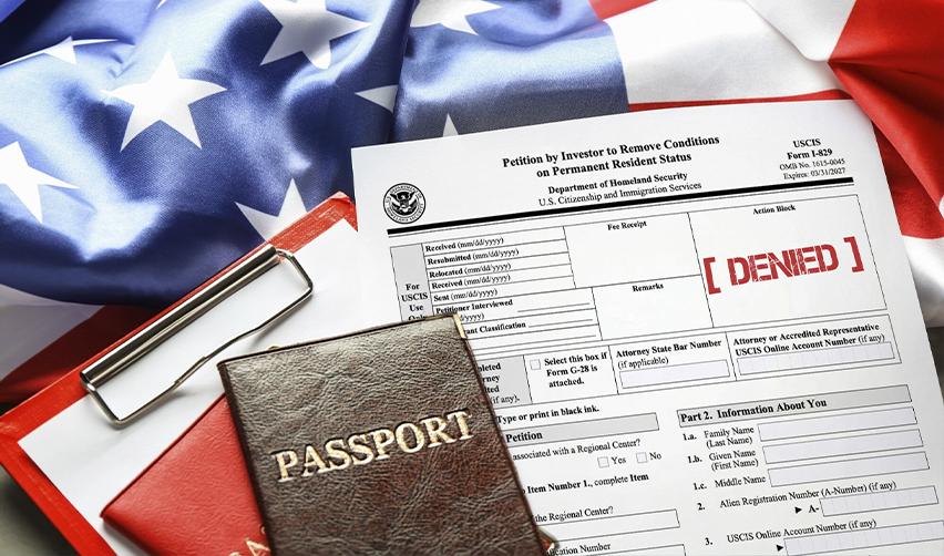 A denied Form I-829 petition with passports on a clipboard, symbolizing EB5 Green Card rejection and immigration consequences.