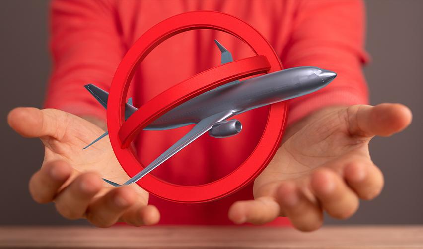 A person holds a symbolic travel ban icon featuring a red crossed-out airplane, representing President Trump’s immigration restrictions and the concerns raised by EB-5 investors amid new legal challenges.
