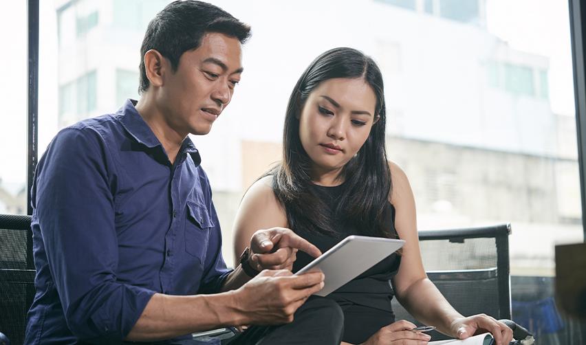 Two professionals reviewing EB5 investment options on a digital tablet, symbolizing guidance through the EB5 visa process.