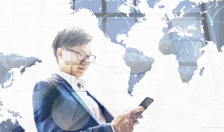 A businessperson stands in front of a digital world map using a smartphone, symbolizing global mobility concerns for EB5 investors from affected countries and ongoing legal challenges to President Trump’s executive order.