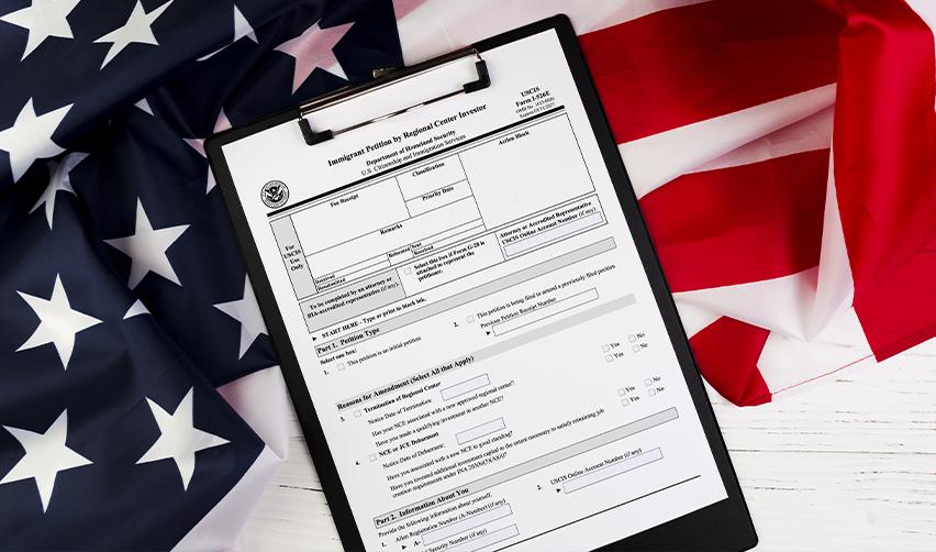 EB5 Form I-526E application form on a clipboard with an American flag, illustrating the U.S. immigrant investor petition process.