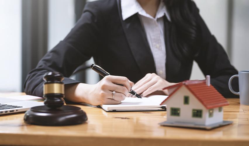 A legal advisor reviewing real estate documents with a small house model and judge’s gavel nearby, illustrating legal and immigration planning for EB5 investors buying U.S. property.