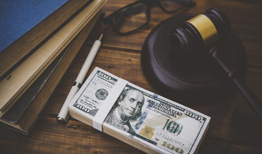 Stack of hundred-dollar bills beside a gavel and legal documents, representing lawful source of funds and EB5 investment compliance.