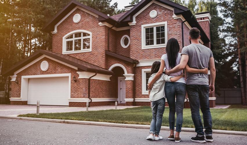 A family standing in front of a newly purchased home, highlighting the long-term relocation goals of EB5 investors entering the U.S. housing market.