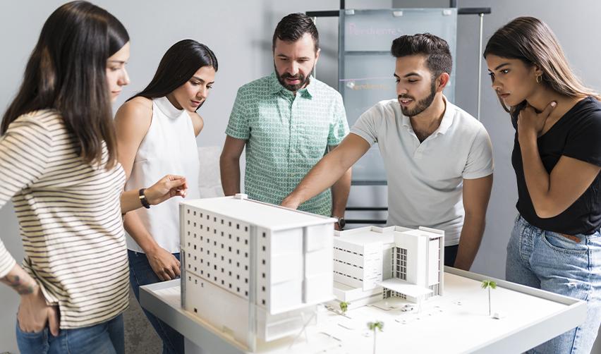 Group of investors reviewing an architectural scale model, reflecting real estate development in EB5 regional center projects.