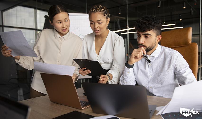 The EB5AN logo next to a team of EB5 advisors analyzing investment documents and job creation data, helping clients avoid I829 petition denial.