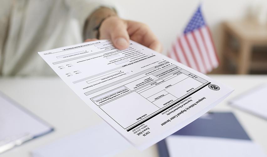 Close-up of a person submitting a USCIS immigration petition form, representing the beginning of the EB5 process in the rural category.