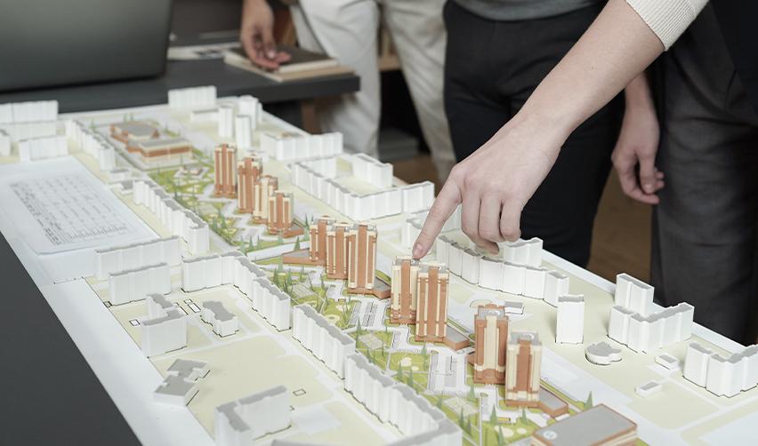 A group reviewing a 3D model of an urban development plan, symbolizing EB5 project site selection in TEA-designated areas.