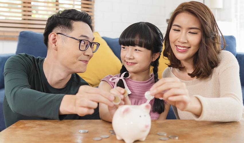 A smiling family placing coins in a piggy bank, symbolizing long-term financial planning and future investment through the EB5 program.