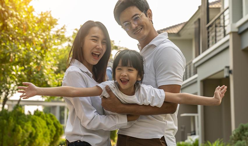 A smiling family standing outside their suburban home, symbolizing the lifestyle benefits and family security offered through the EB5 regional center program.