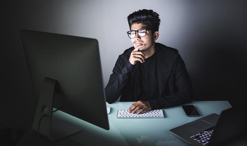 Indian H1B tech professional considering EB5 visa options at computer desk, representing career transition from employment to entrepreneurship.