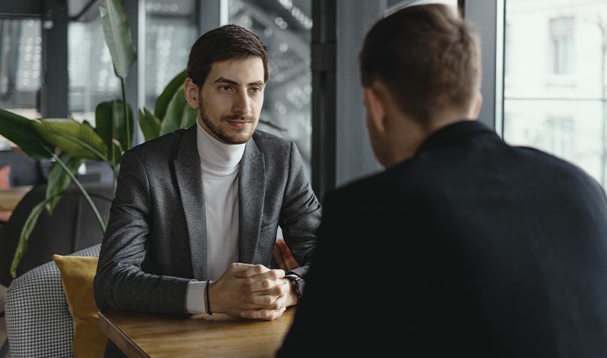 A professional conversation between two men in a modern office setting, symbolizing an EB5 investor discussing immigration options with an employer.