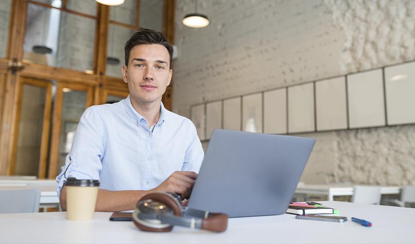 A young professional working on a laptop in a modern office space, representing a qualified U.S. worker eligible for job creation under EB5 rules.