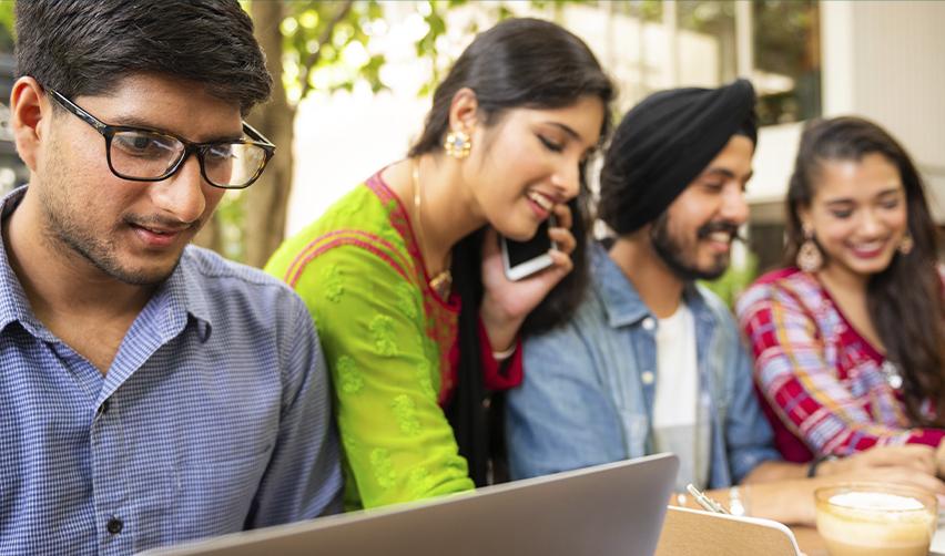 Group of young Indian professionals collaborating on laptops and phone, representing skilled workers exploring EB5 visa options beyond the H1B lottery.