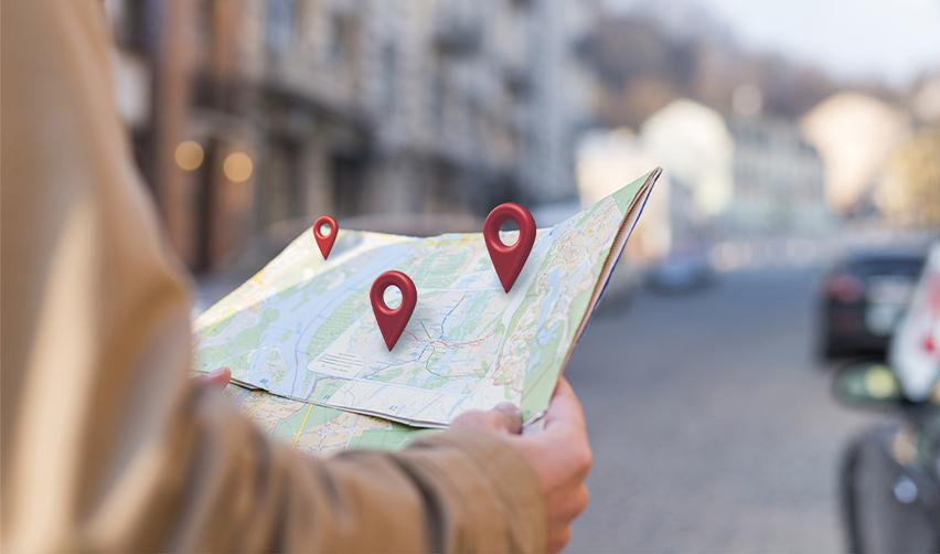 Person holding a paper map with location pins, symbolizing EB5 investors choosing where to live in the United States.