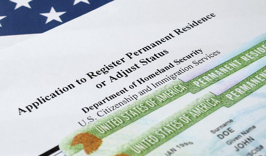 Close-up of a U.S. permanent residence application and Green Card, highlighting EB5 adjustment of status process.