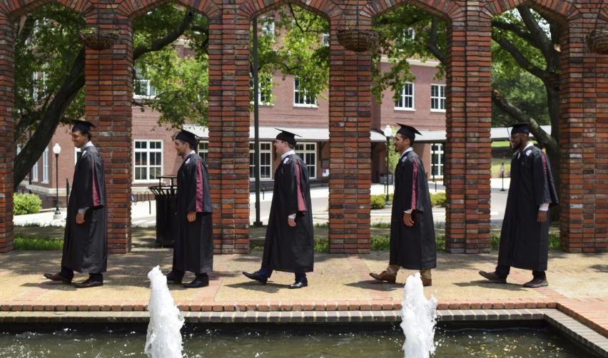Group of university graduates in caps and gowns walking together on campus, highlighting how EB5 Green Card status supports long-term education and career opportunities in the U.S.