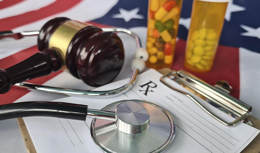 A gavel, stethoscope, prescription form, and pill bottles placed on top of the U.S. flag, representing the legal and visa requirements for foreign doctors in the United States.