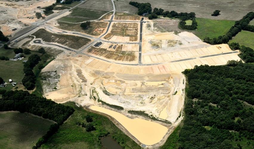Progress at Rocky River EB5 project with newly paved roads, graded home sites, and retention ponds, highlighting infrastructure development in this 55-plus community.