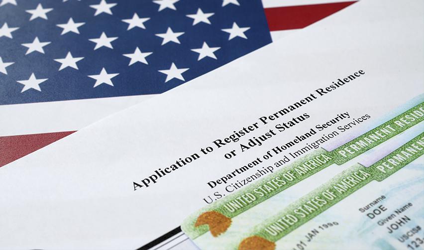 Close-up of a U.S. permanent residency application form and Green Card on an American flag background, representing the EB5 immigration process.