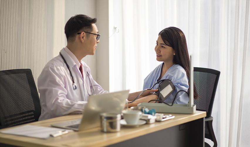 A foreign doctor or international medical graduate in a white coat taking a patient’s blood pressure during a consultation after completing his graduate medical education, representing the pathway to practicing medicine after obtaining U.S. licensure.