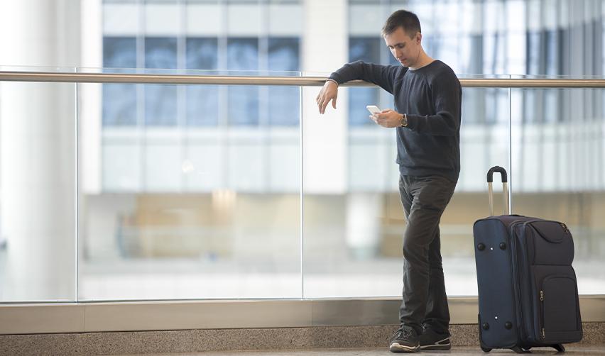 Man standing in an airport terminal with luggage, representing EB5 applicants considering travel and Advance Parole requirements.
