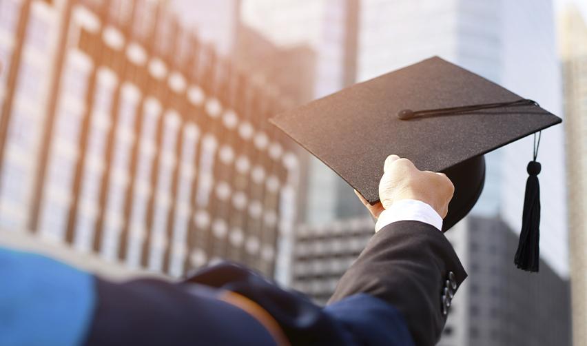 Graduate holding a mortarboard cap against a city skyline, illustrating EB5 students transitioning from F-1 visa to permanent residency.