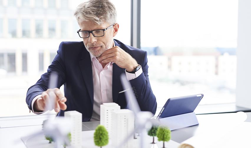 Businessman reviewing real estate models, highlighting planning and financial projections in EB5 projects.