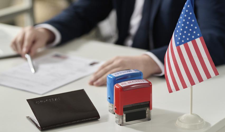 Close-up of a U.S. flag and visa application paperwork with approval and rejection stamps, symbolizing EB5 immigration outcomes and the importance of accurate filings.