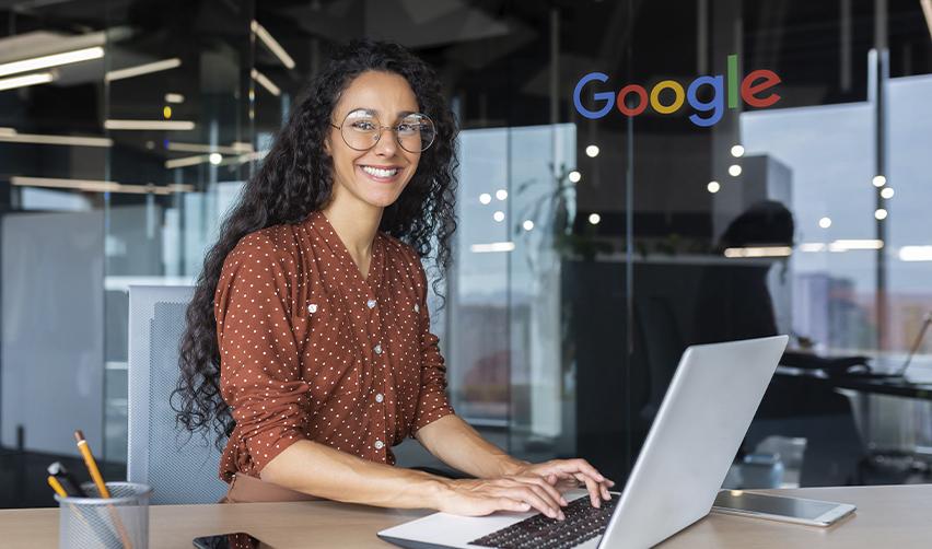 A smiling professional working on a laptop inside a Google office, representing Indian H1B employees exploring EB5 as an alternative to employment-dependent visas.
