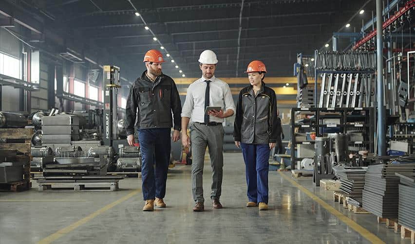 Engineers and construction managers reviewing project plans inside a manufacturing facility, representing direct job creation from EB5-funded developments.