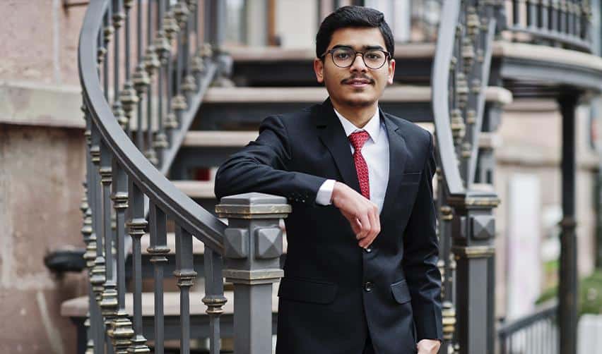 A confident professional in a suit standing by a staircase in a U.S. city, representing skilled workers seeking stability and opportunity through the EB5 investment visa.