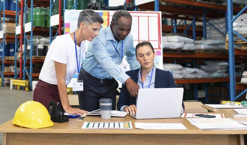 Project managers and analysts collaborating in a warehouse office environment, reflecting coordination and indirect employment generated by EB5 projects.