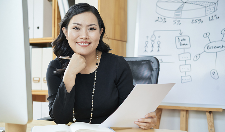 A professional woman reviewing documents in an office, symbolizing EB5 investors preparing paperwork for the J1 to Green Card process.