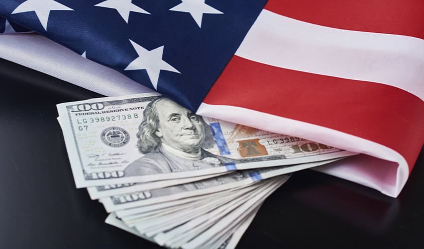 U.S. flag draped over a stack of hundred-dollar bills, illustrating the EB5 investment requirement for J1 visa holders seeking permanent residency.