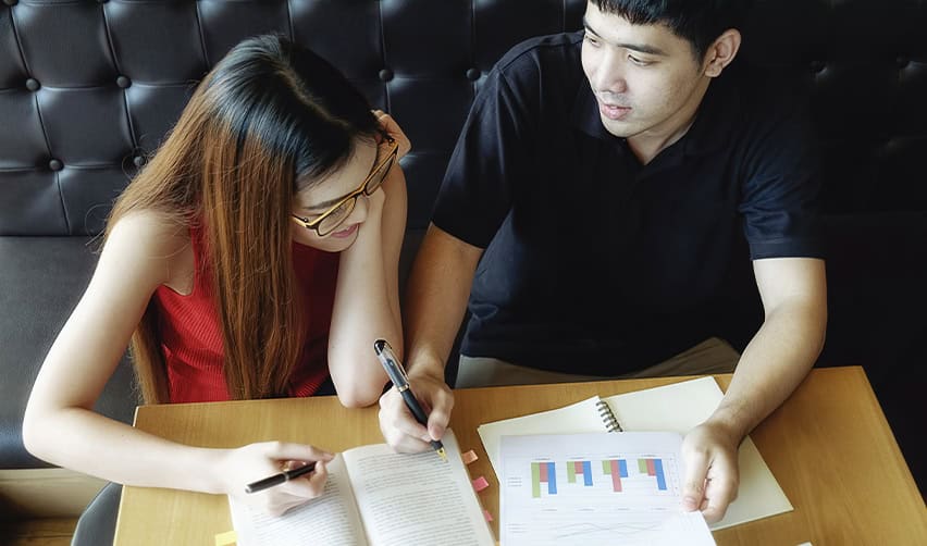 Two students reviewing charts and textbooks, symbolizing J1 exchange visitors exploring long-term immigration options including EB5.