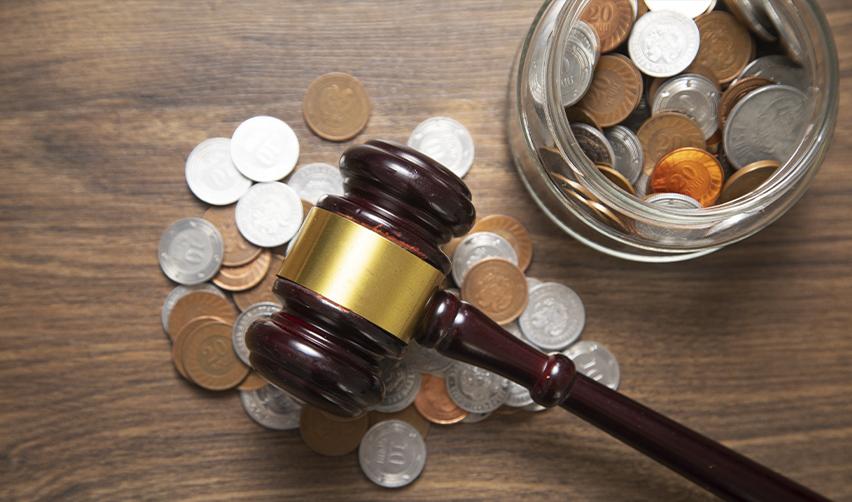 A judge’s gavel resting on scattered coins beside a jar of change, symbolizing the court ruling that restored lower EB5 filing fees for investors.