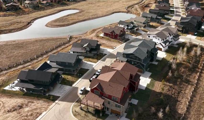 Aerial view of a Grand Park residential district built along a winding water feature, displaying completed single-family homes and landscaped lots.