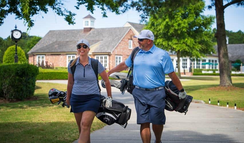 Golfers walking toward the Bay Creek clubhouse on a sunny day, representing the active lifestyle and premium amenities of the Bay Creek EB5 project.