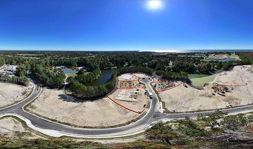 Wide aerial panorama of Bay Creek showing multiple housing sections under development beside golf fairways and waterways, representing ongoing EB5 community expansion.