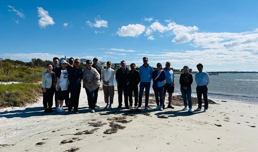 A group of EB5 investors, attorneys, and partners standing together on Bay Creek’s private beach under a bright blue sky, symbolizing community and connection during the site visit.