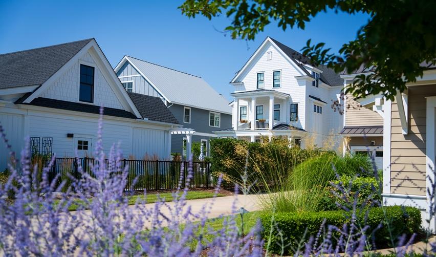 Coastal-style homes at the Bay Creek rural EB5 project with bright landscaping and shaded walkways, reflecting the community’s residential appeal and year-round lifestyle.