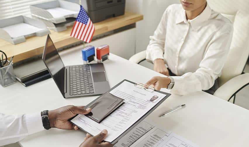 An investor submitting immigration forms at a desk with a U.S. flag, representing EB5 application processing and compliance verification.