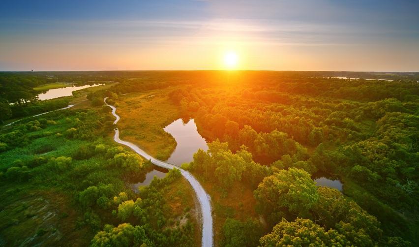 Sunset aerial view of Bay Creek’s nature preserve with winding trails and waterways, highlighting the project’s commitment to sustainability and environmental stewardship through the EB5 program.