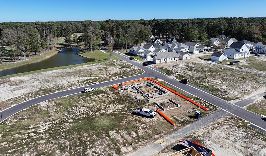 Aerial view of new home foundations under construction at Bay Creek, showing roadways, nearby homes, and water features within the coastal EB5 community in Cape Charles, Virginia.