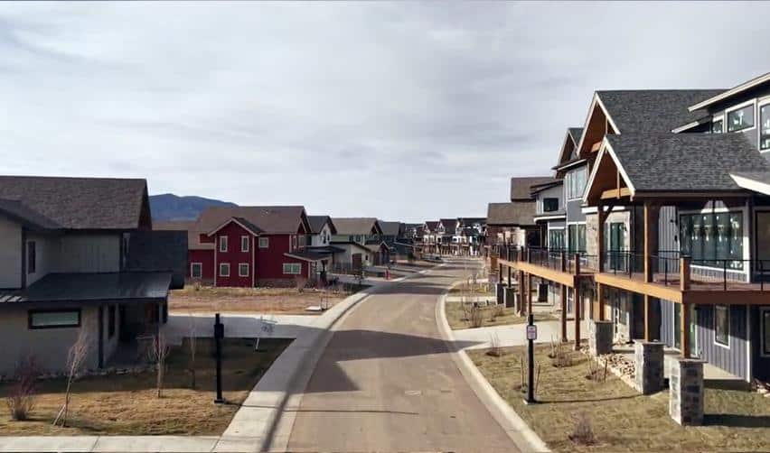 A street-level view of finished homes at Grand Park, featuring wide roads, front porches, and the surrounding alpine backdrop.