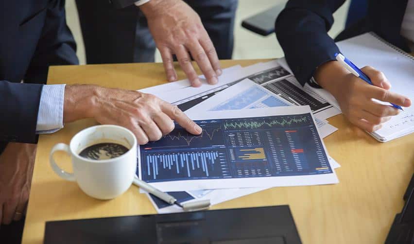 Business professionals reviewing financial dashboards and market data, illustrating how AI supports EB5 project financial assessment and forecasting.