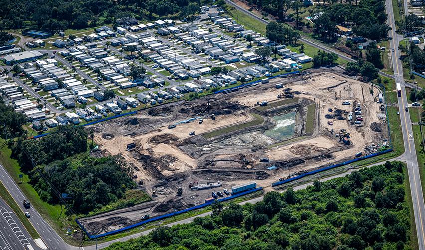 A wide aerial view of the Terra Ceia Multifamily EB5 construction site in Palmetto, Florida, showing cleared land, heavy equipment, and early grading work surrounded by nearby residential neighborhoods.