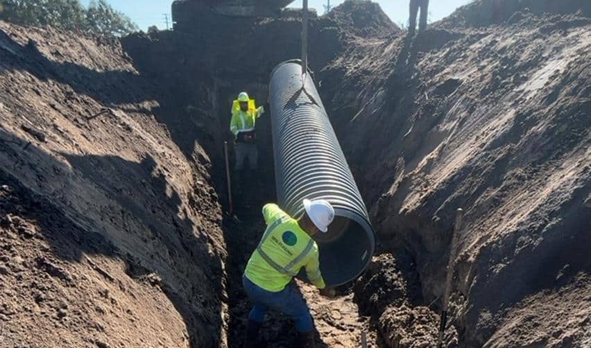 Crew members installing a large storm drainage pipe at the Terra Ceia Multifamily EB5 project, lowering it into a deep trench as part of ongoing underground utility work.